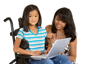A young girl sitting in a wheelchair and her Mom working on a laptop